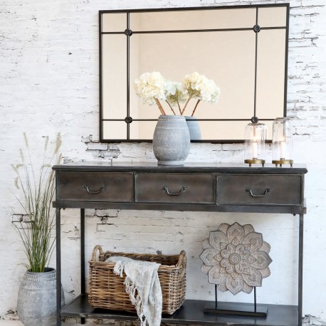 Duże lustro z ozdobnymi szprosami ma kształt prostokąta i ramę w ciemnym kolorze.