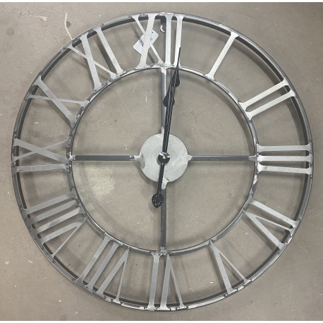 Ażurowy zegar metalowy najlepiej zawiesić na jednolitym tle.