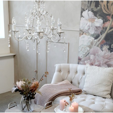 Żyrandol prowansalski wykonany z metalu o zaokrąglonych liniach i zawieszonych na nim kryształkach.