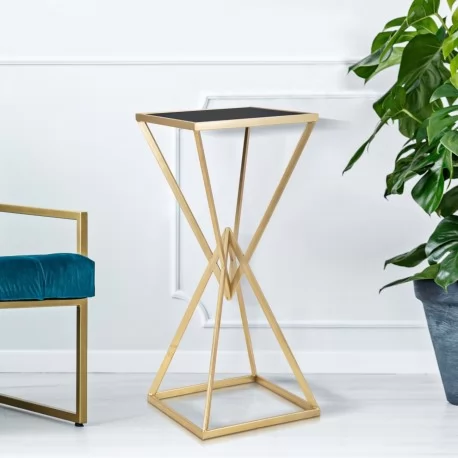 Ten złoty stolik w kształcie piramidy posiada czarny blat.