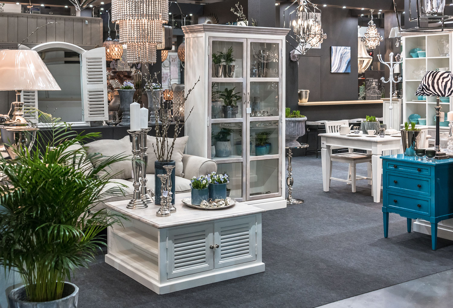 Jadalnia urządzona meblami Belldeco z kolekcji Bristol White – drewniany stół z krzesłami w odcieniach bieli i naturalnego drewna, witryny i komody ze szklanymi frontami, uzupełnione eleganckimi dodatkami i lampami w stylu prowansalskim