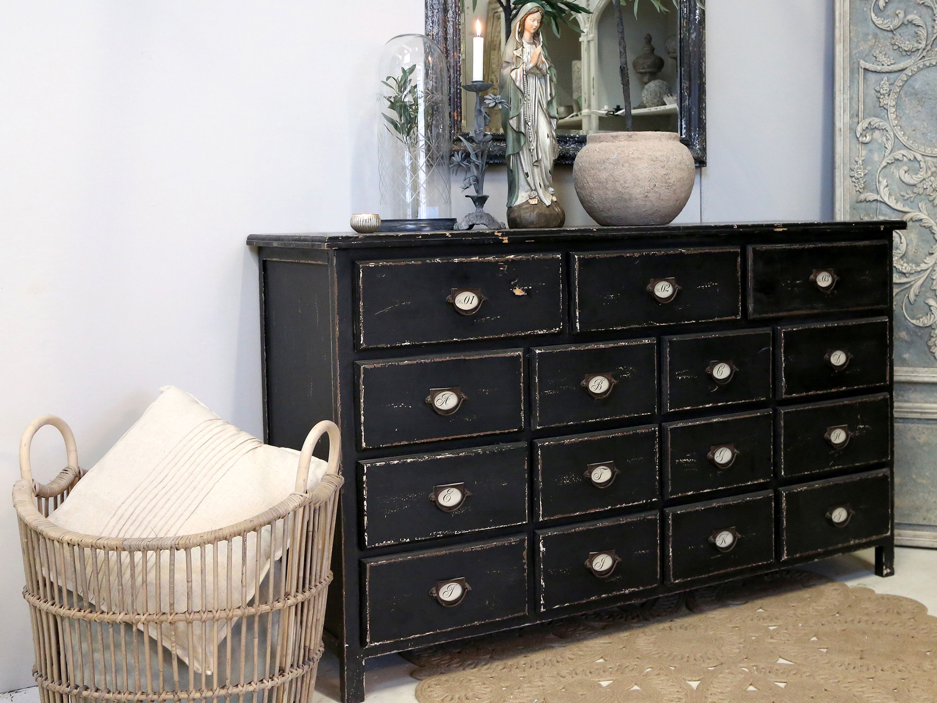 Czarna komoda z przetarciami i wieloma szufladami to wyjątkowy mebel vintage, który dodaje wnętrzu charakteru i elegancji w stylu retro.